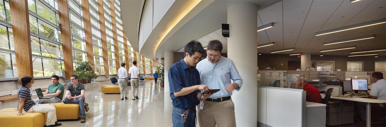 Two male students examine an iPad in an academic building