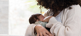 Mom holds baby snugly while breastfeeding.