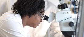 Drexel University College of Medicine Pharmacology and Physiology graduate student looking into a microscope.