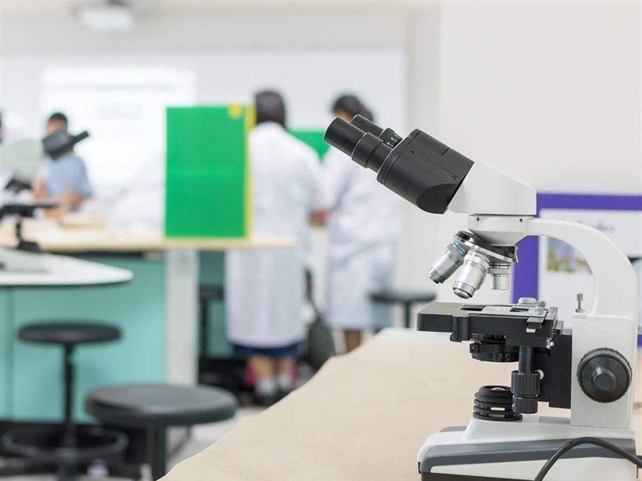 Microscope in a lab with people in lab coats in background
