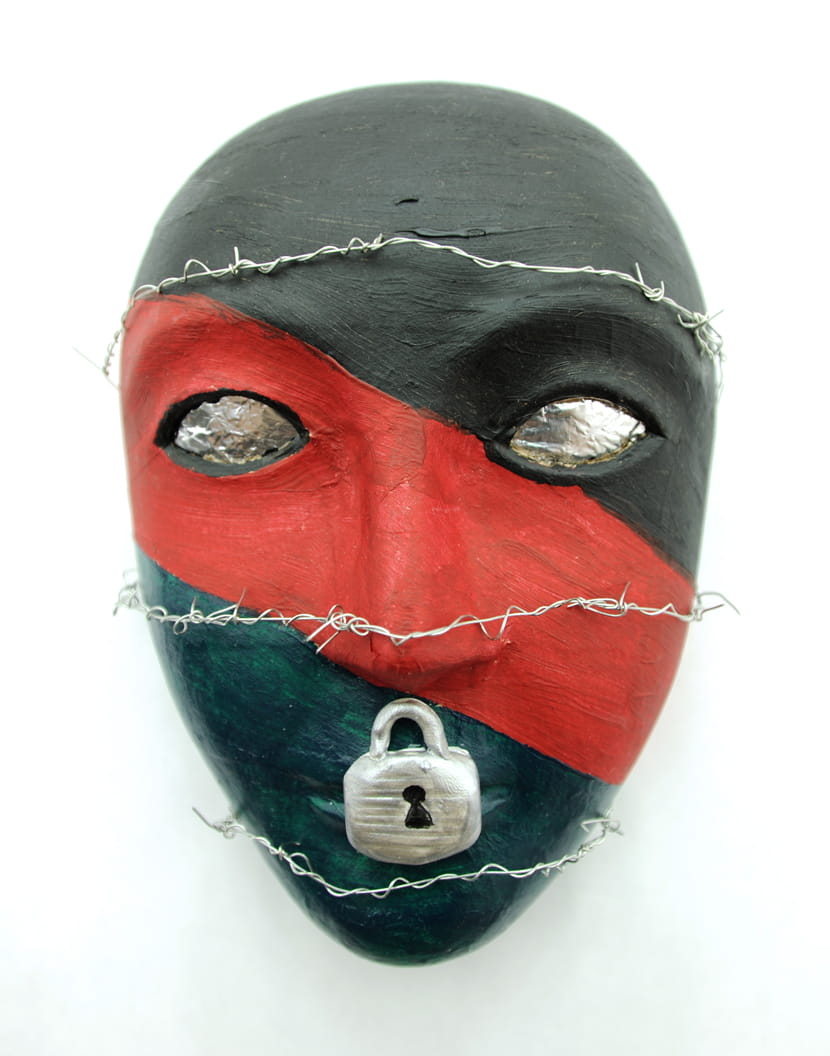 A red and black mask with a lock over the lips and razor wire wrapped around the face. One of the masks created by a U.S. military service member as part of an art therapy program being analyzed by Girija Kamal, of Drexel's College of Nursing and Health Professions.