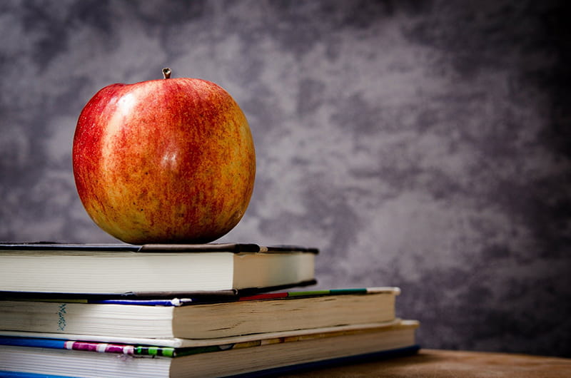 Red apple sitting on a pile of three books