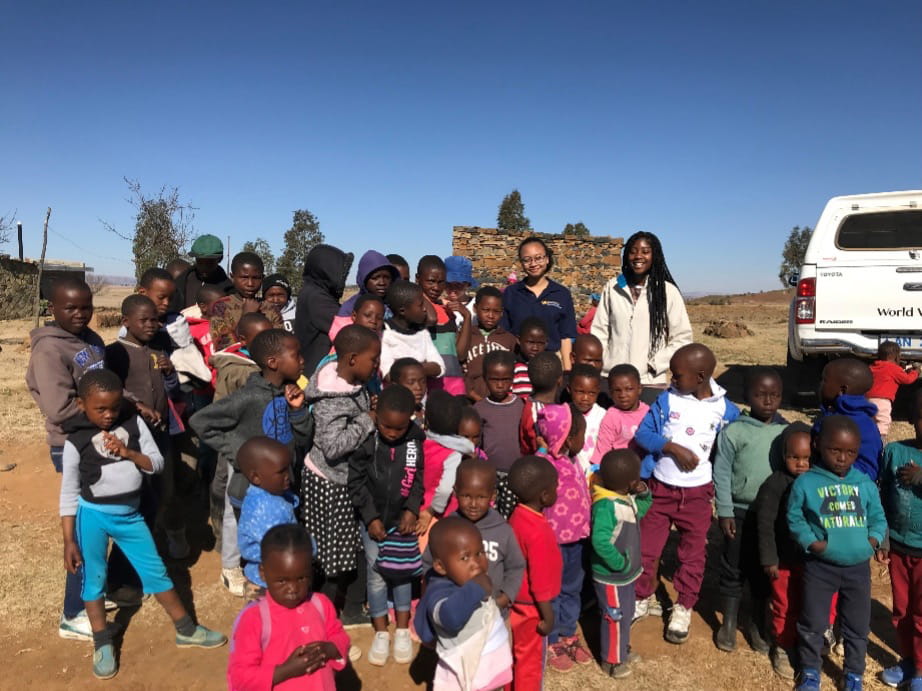 A group of children outside with two adult women.