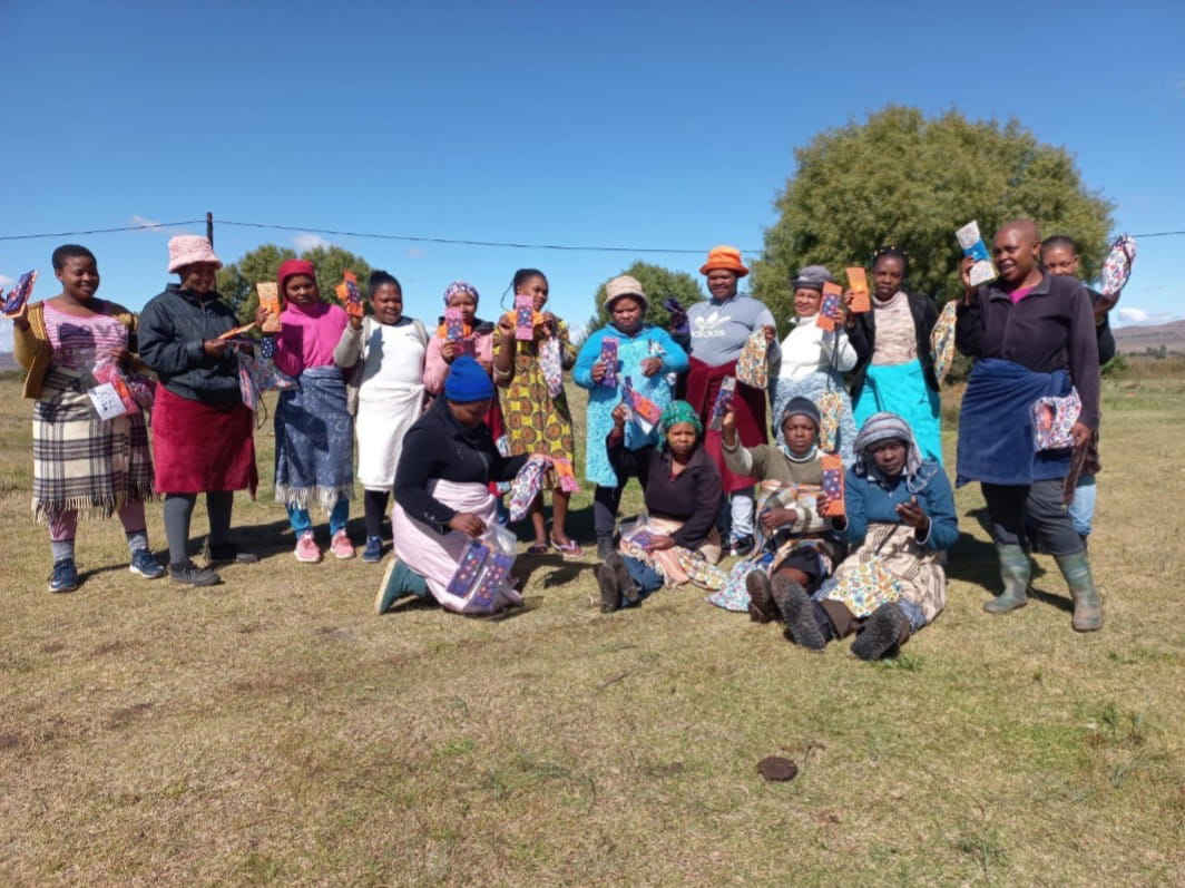 Women sitting and standing outside and holding cloth pads.