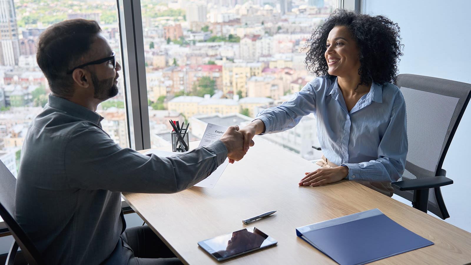 man and woman shaking hands across a desk