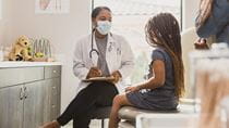 Young girl in doctors office with doctor and parent 