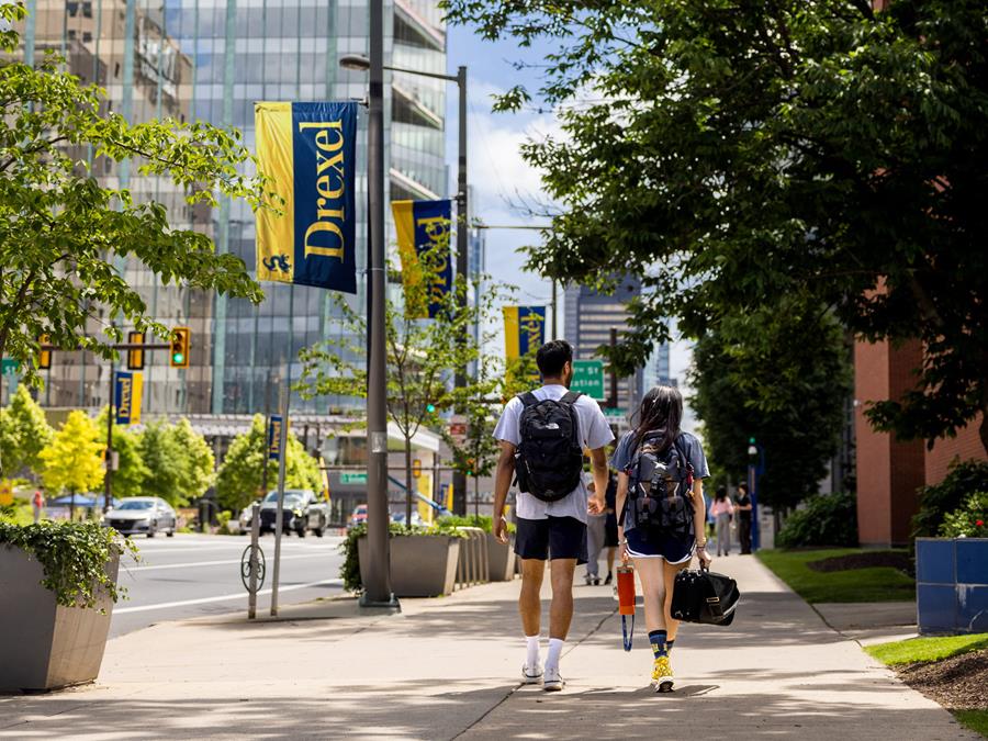 Two students walking on the sidewalk near campus.