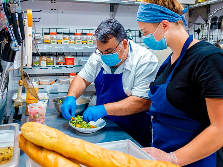 Executive chef Brian Lofink ’03 and Drexel University fifth-year and co-op student Anna Wilson plate a panzanella salad in the kitchen of terrain’s garden café in Glen Mills, Pennsylvania