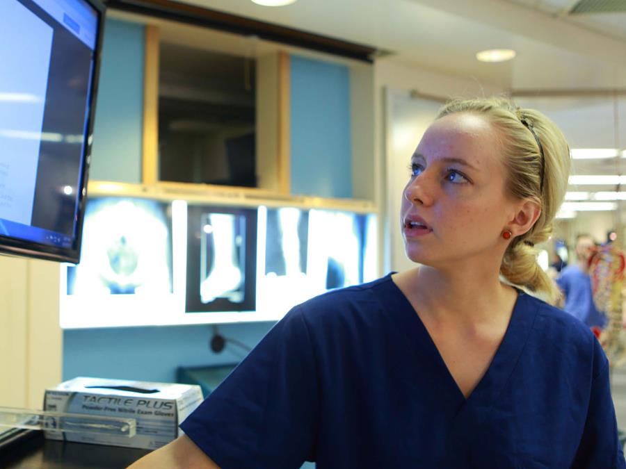 Student in a hospital setting looking at a computer monitor