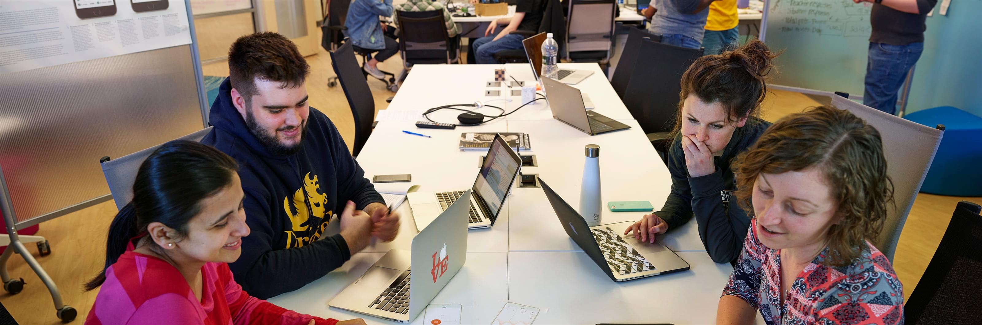Students sitting at a table while working on their laptops