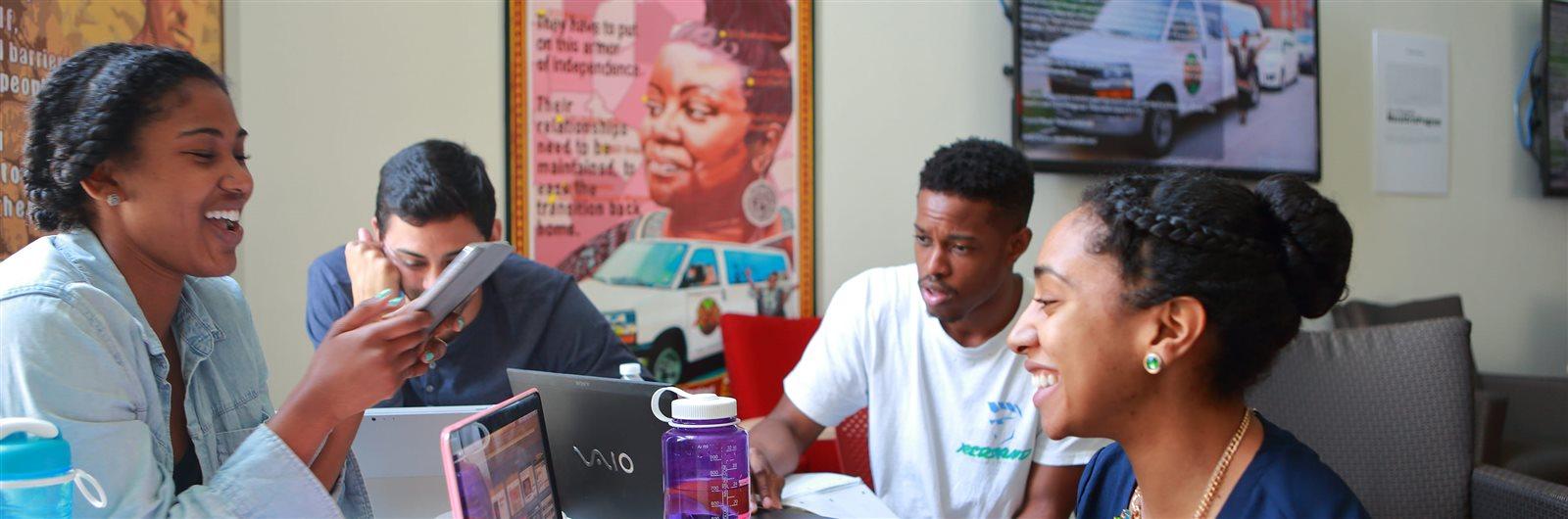 Students sitting at a table and looking at their devices
