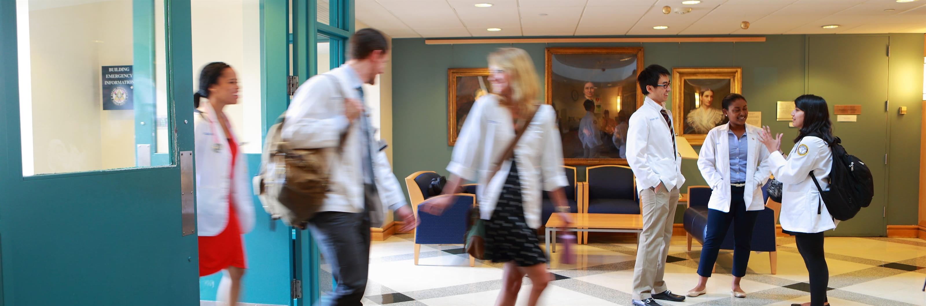 Students dressed in white coats in lobby of College of Medicine