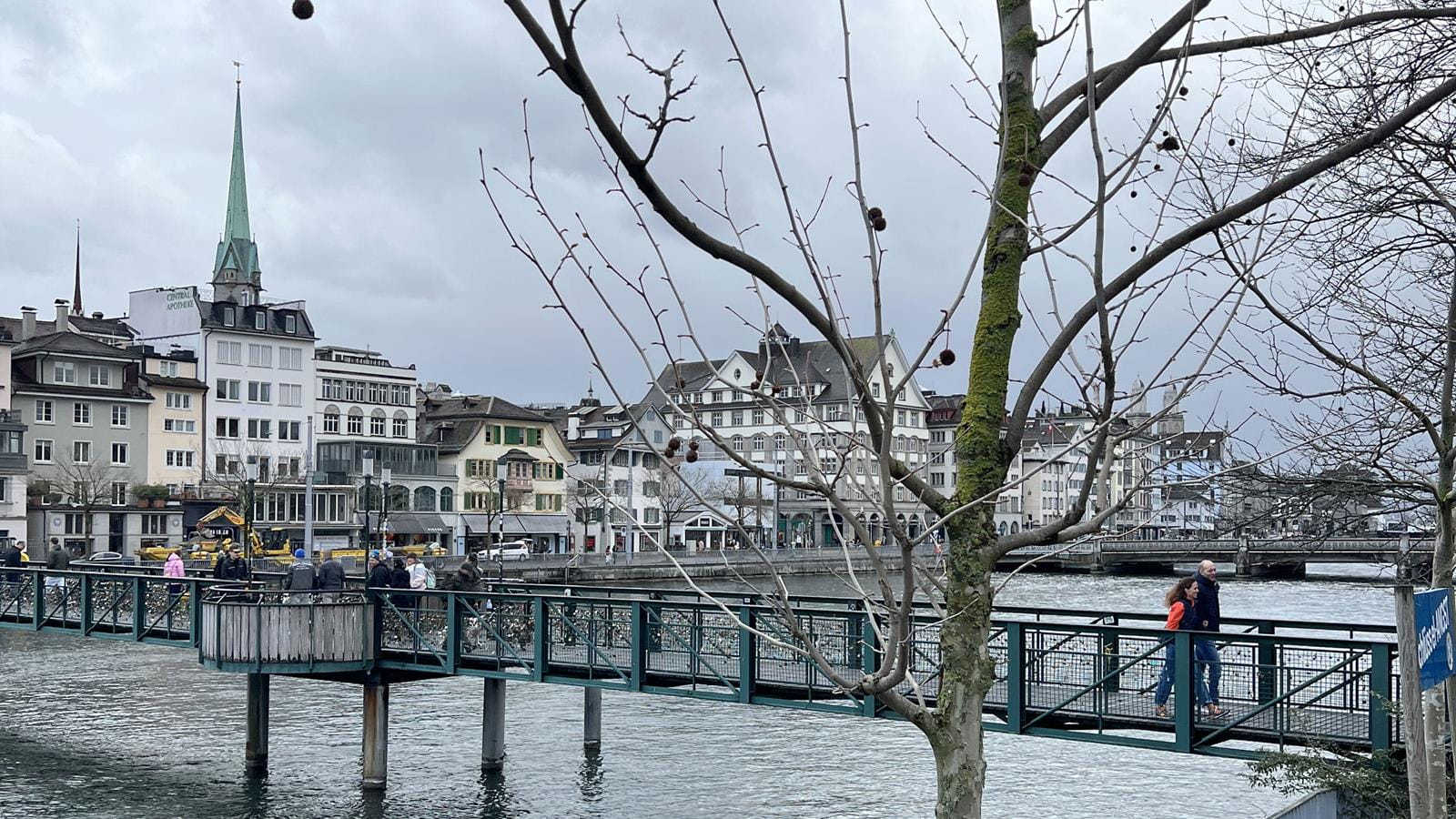 People walking across a bridge in a city in Switzerland