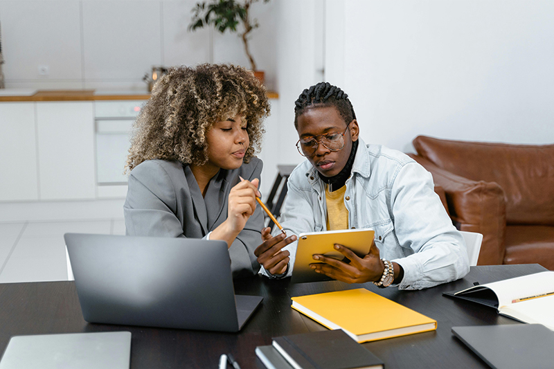 Two people going over documents at a computer