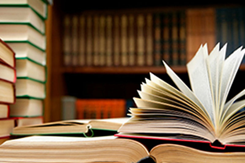 Books piled and opened on a table in a library