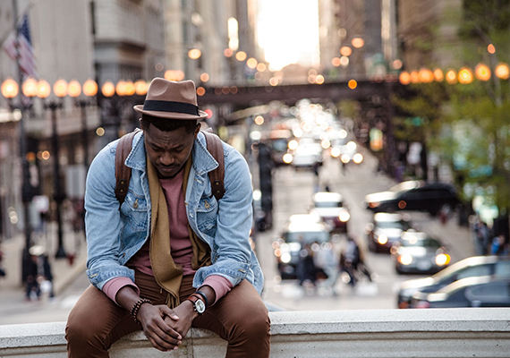 Man sitting on a ledge overlooking a city street