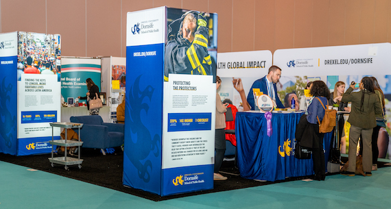 Dornsife enrollment team talks to attendees at school's booth during APHA 2019