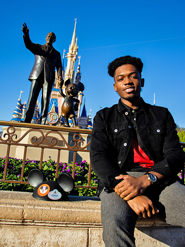 Young man in front of statue of Walt Disney and Mickey Mouse