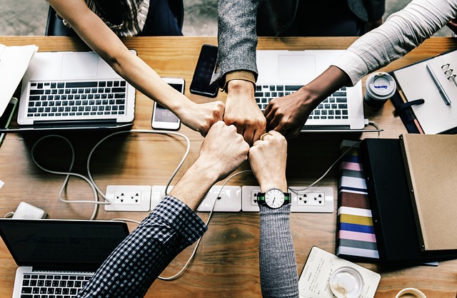 Image of 5 people hand-fisting over laptops