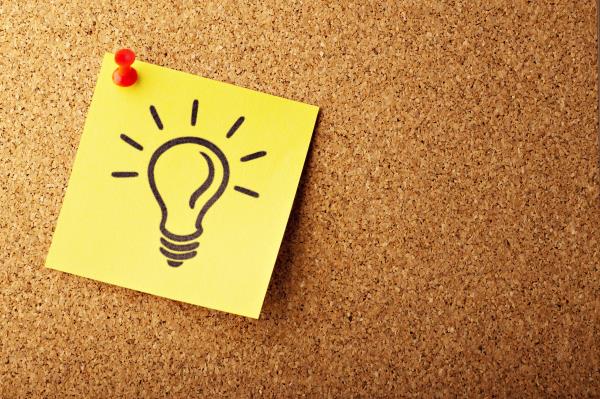 Lightbulb drawn on a sticky pad placed on a cork board