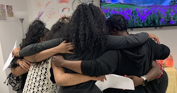 Group of women in a circle with their arms around each other