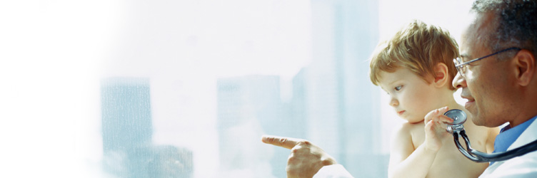 Doctor holding toddler boy pointing out of window.