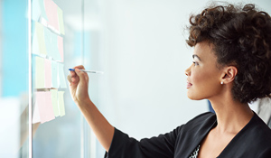 Businesswoman making notes on a glass board.