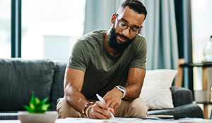 Man writing at coffee table.