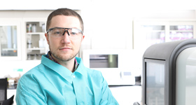 Graduate student in a laboratory, next to equipment, at Drexel University College of Medicine.