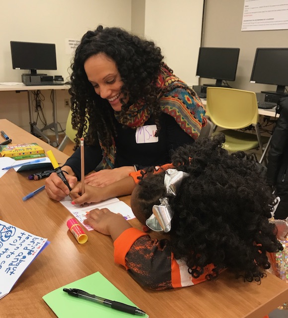 An instructor helps a young girl with a project